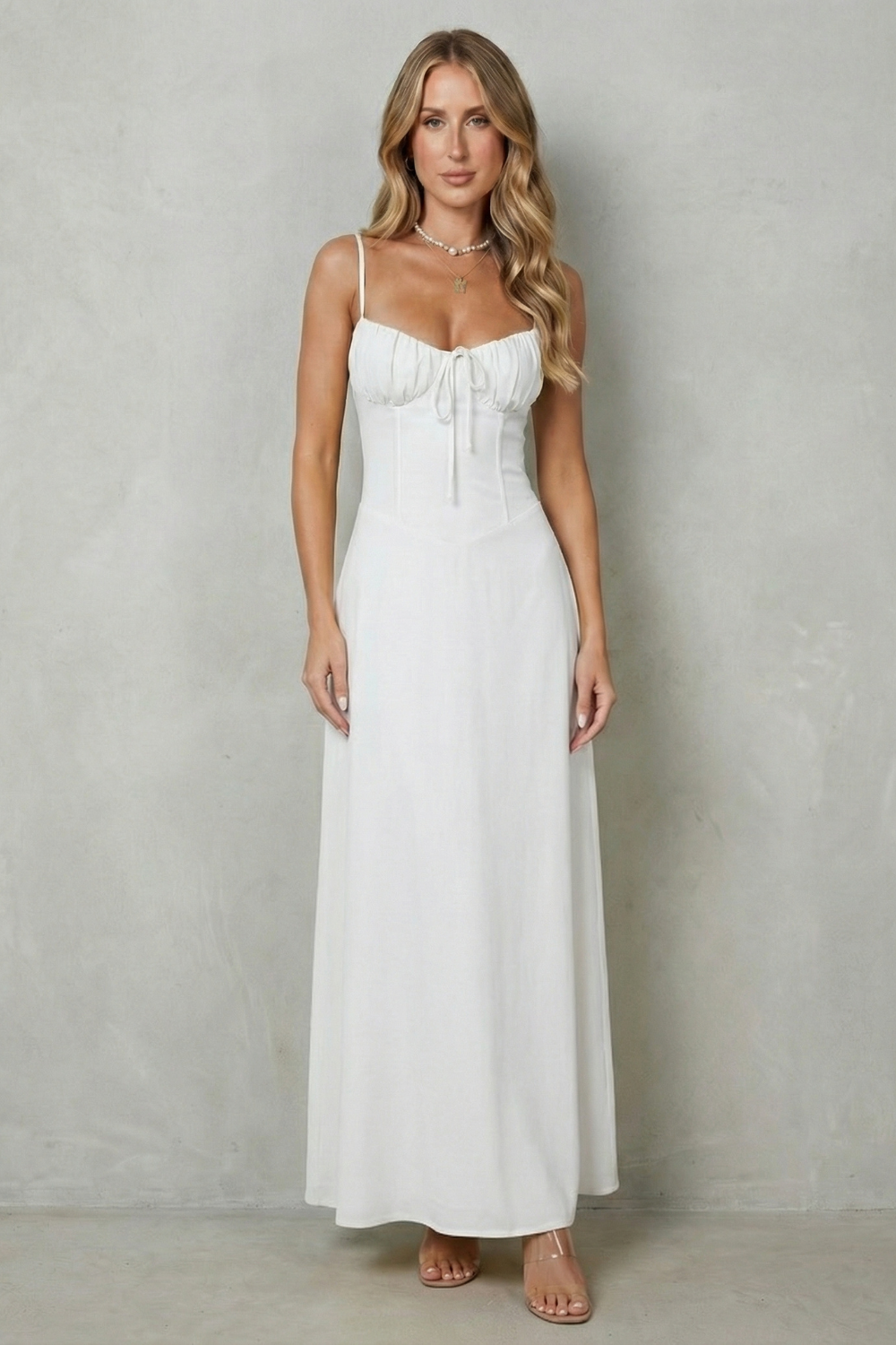 White corset maxi dress with thin straps, gathered bust, and front tie at waist