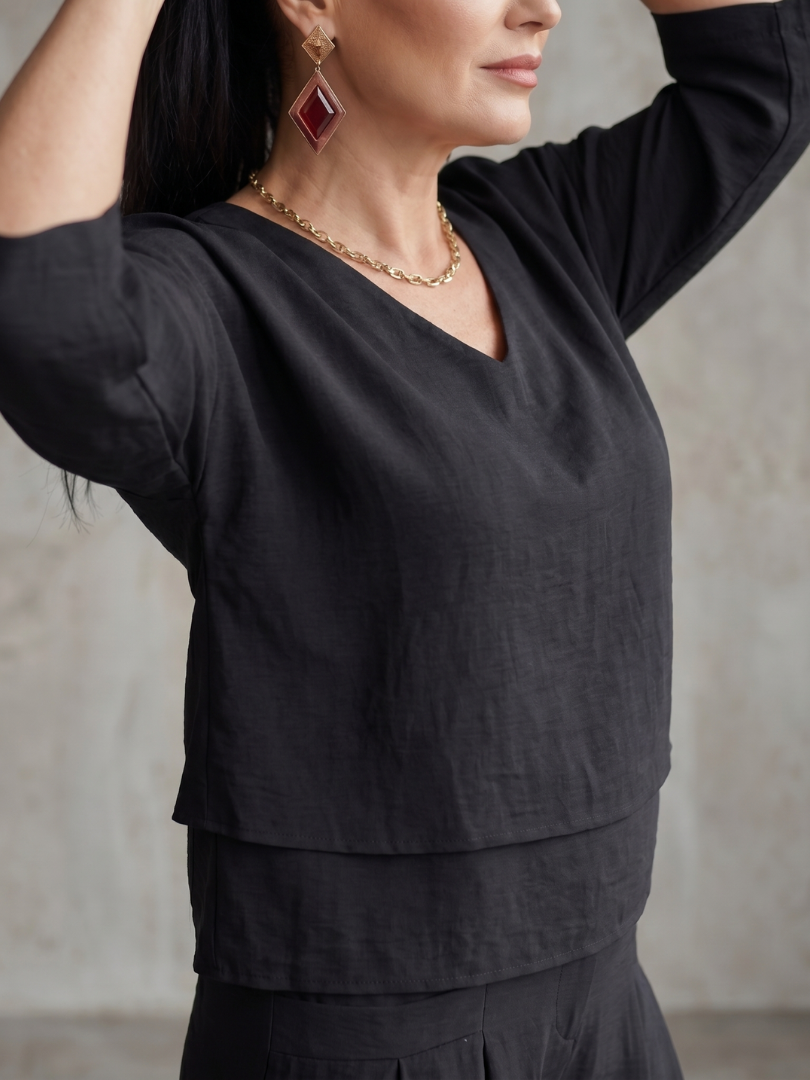 Black wide-leg pants set top with V-neck, three-quarter sleeves, and layered hem detail.