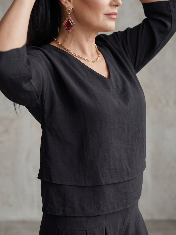 Black wide-leg pants set top with V-neck, three-quarter sleeves, and layered hem detail.