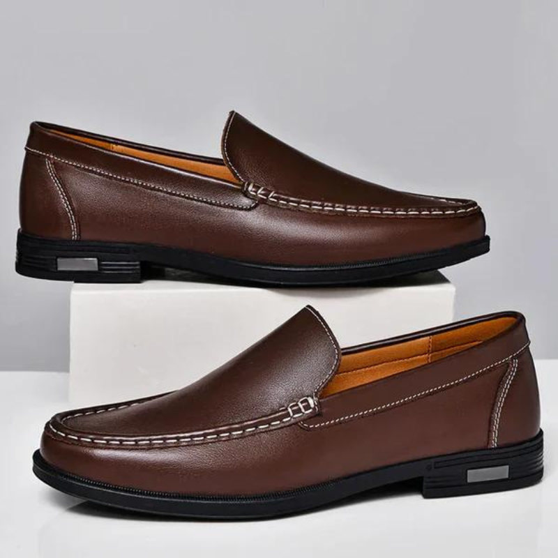Brown leather loafer with metal bar strap, contrast stitching, and textured sole