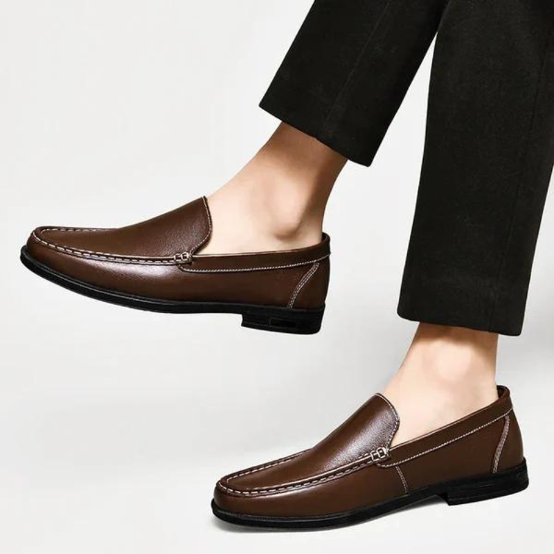 Brown leather loafer with metal bar strap, stitched moc toe, worn with black pants