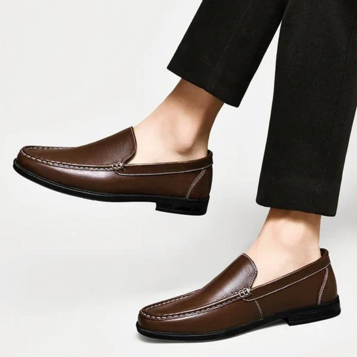 Brown leather loafer with metal bar strap, stitched moc toe, worn with black pants
