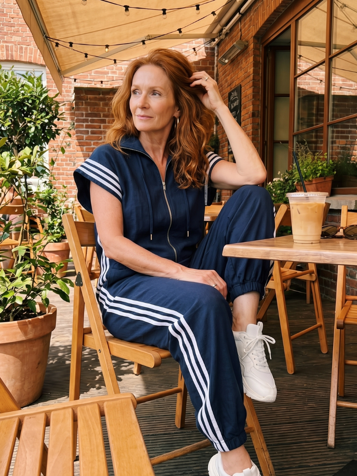 Blue sleeveless zip-front jumpsuit with striped side panels and drawstring hood
