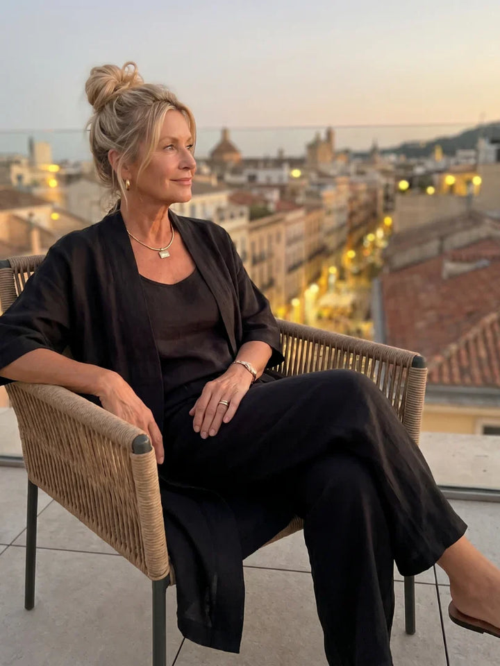 Black lounge set with robe over tank and wide-leg pants while seated