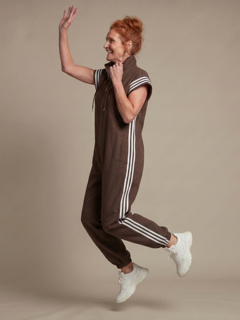 Brown sleeveless zip-front jumpsuit with white striped side panels and drawstring hood