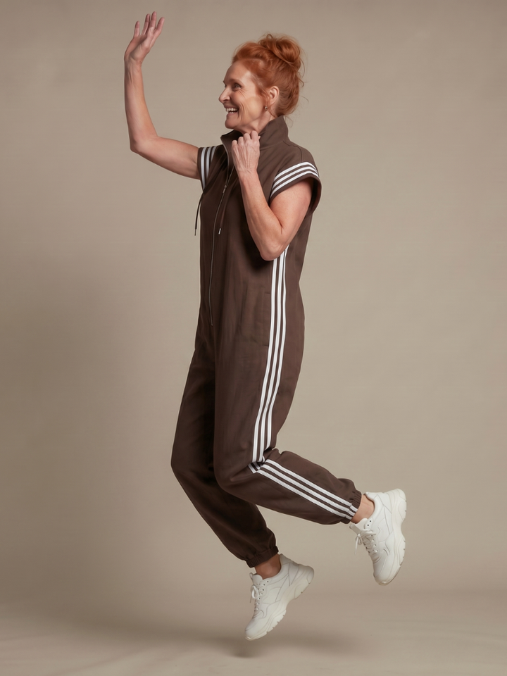 Brown sleeveless zip-front jumpsuit with white striped side panels and drawstring hood