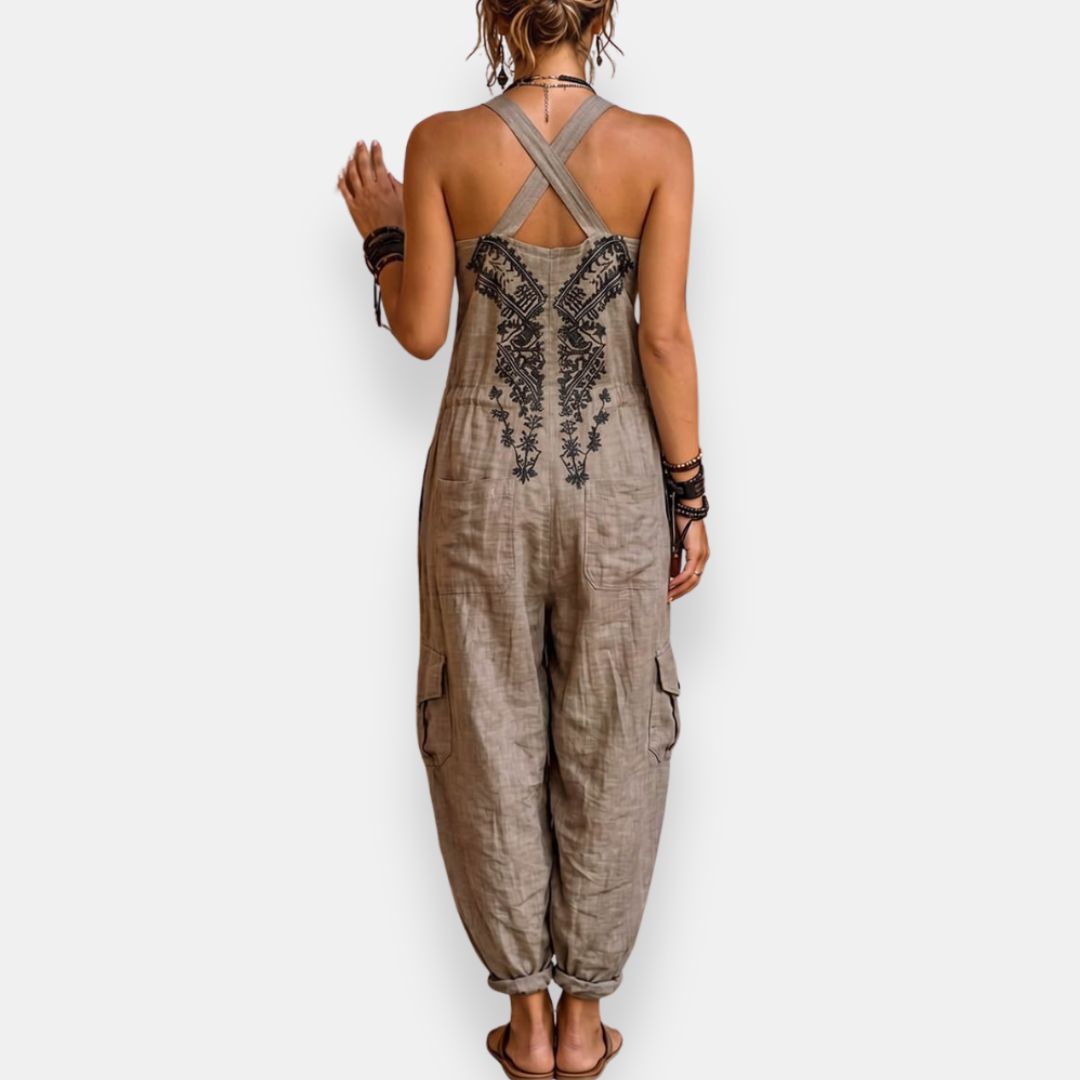 Grey bohemian jumpsuit back view with crisscross straps and embroidered center panel