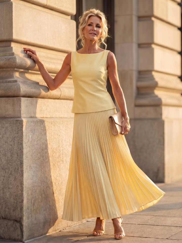 Yellow pleated two-piece set with sleeveless top and pleated midi skirt