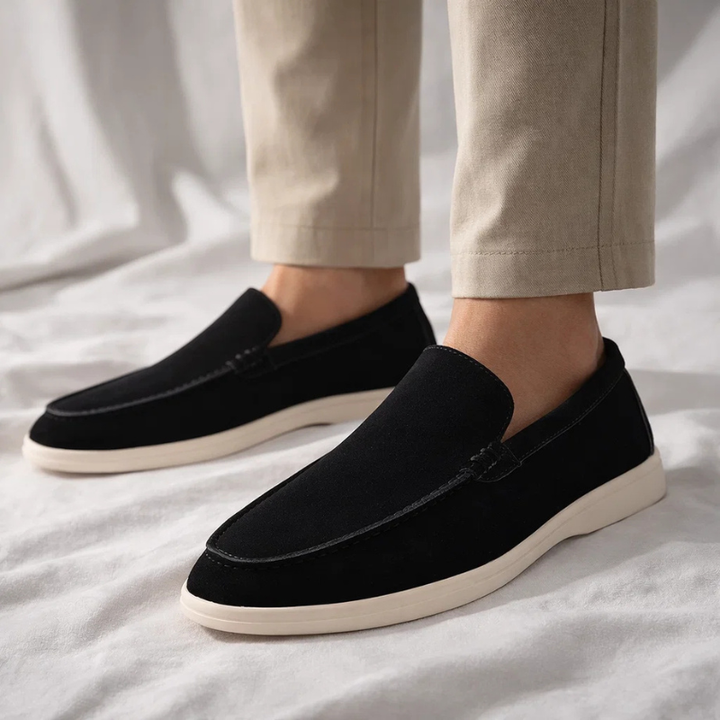 Black suede loafer slip-on worn with pants; stitched moc toe and cream sole
