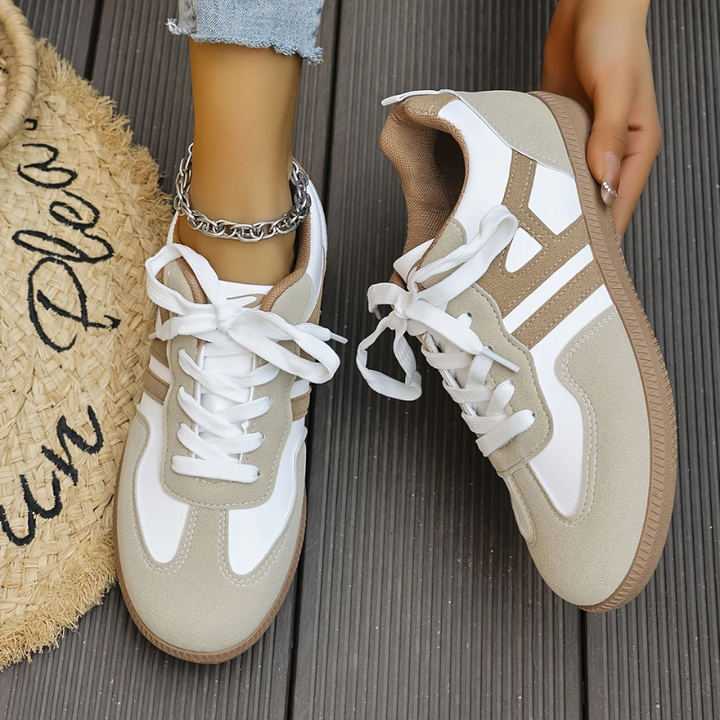 Low top lace-up sneakers with white laces and tan-and-white panels, gum soles