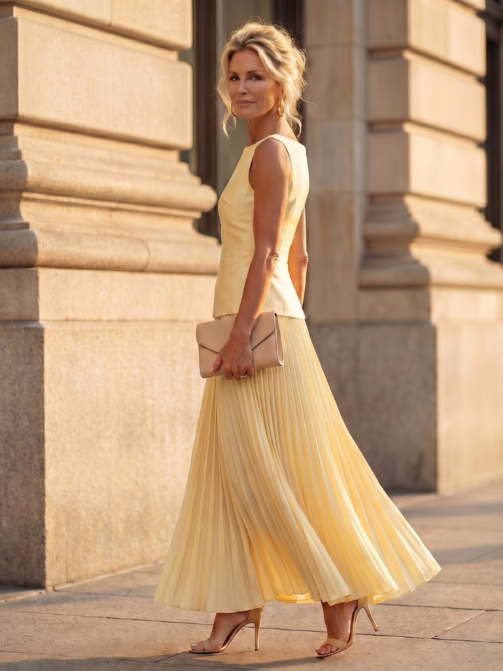Yellow pleated two-piece set with sleeveless top and pleated midi skirt, side view