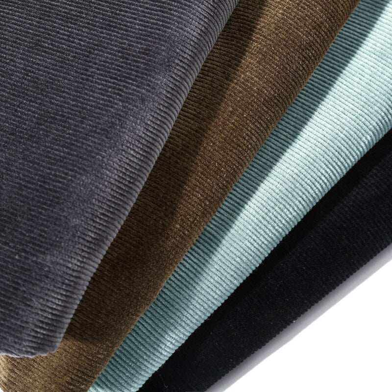 Corduroy fabric close-up with ribbed texture in gray, brown, teal, and dark tones