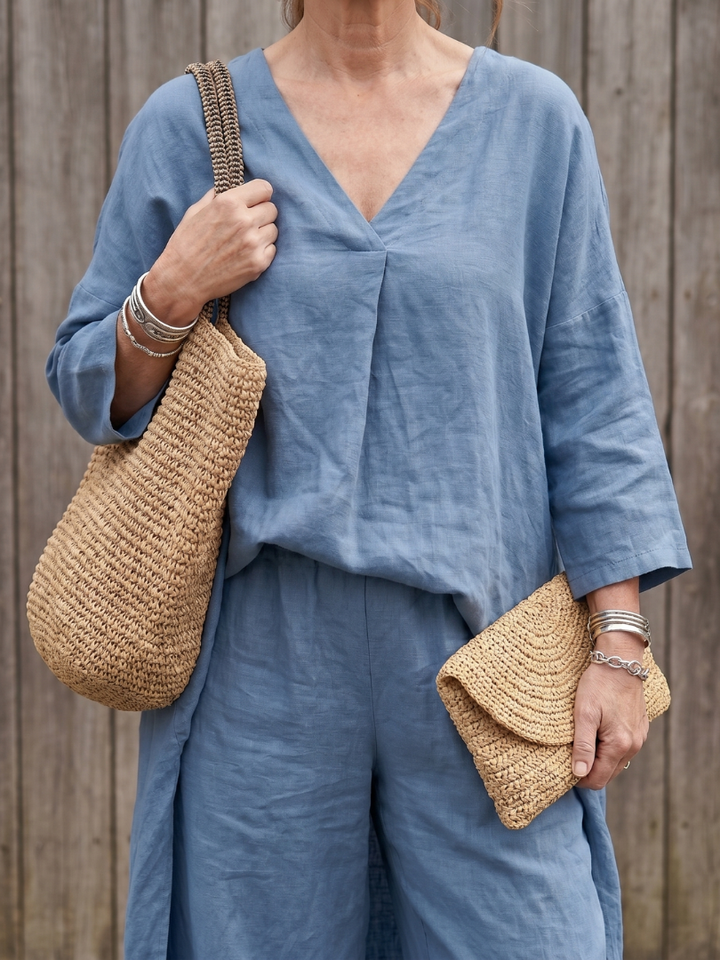 Blue linen two-piece set close-up: V-neck tunic top with folded front and matching pants.