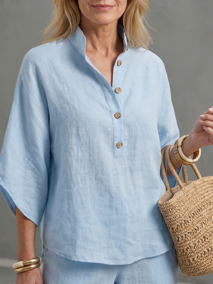 Sky blue button-up blouse top with gold buttons and wide collar, paired with matching pants.