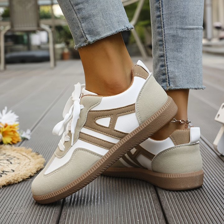 Low top lace-up sneakers with white laces and tan-and-white panels, cushioned heel