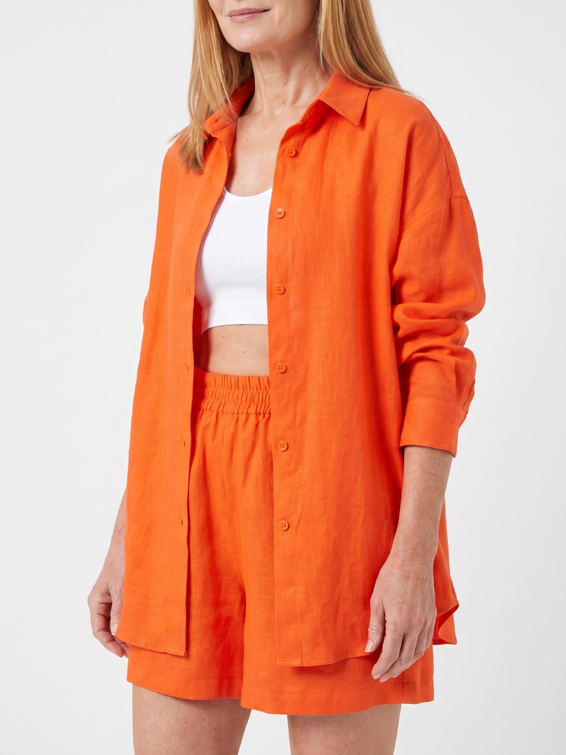 Orange button-front jacket over white crop top with elastic-waist shorts