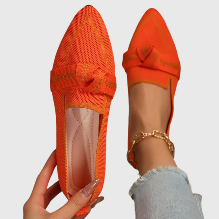 Orange knit loafer shoes with bow strap and perforated knit upper.