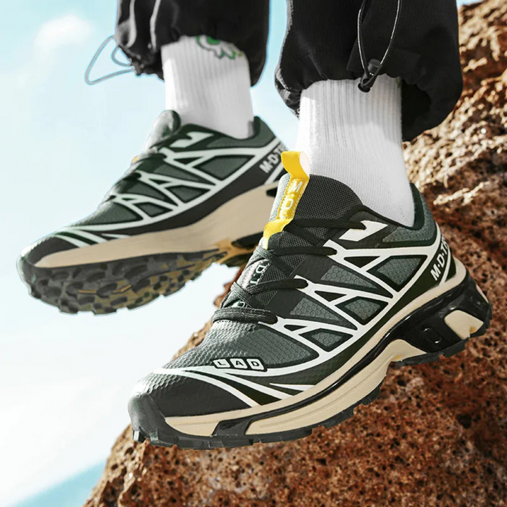 Black lace-up walking sneaker with green trim, white zigzag panels, and yellow pull tab