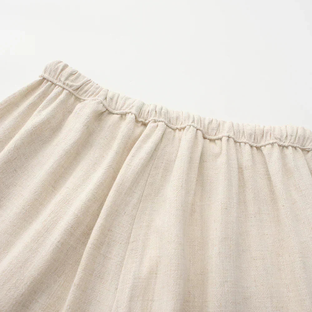 Beige linen pants waistband close-up with elastic casing and drawstring.