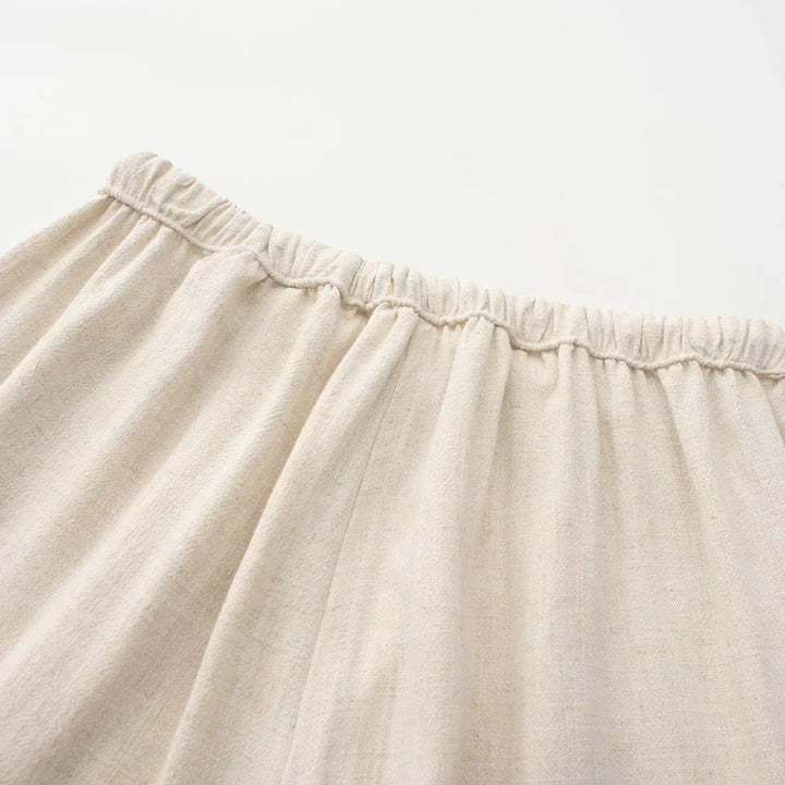 Beige linen pants waistband close-up with elastic casing and drawstring.