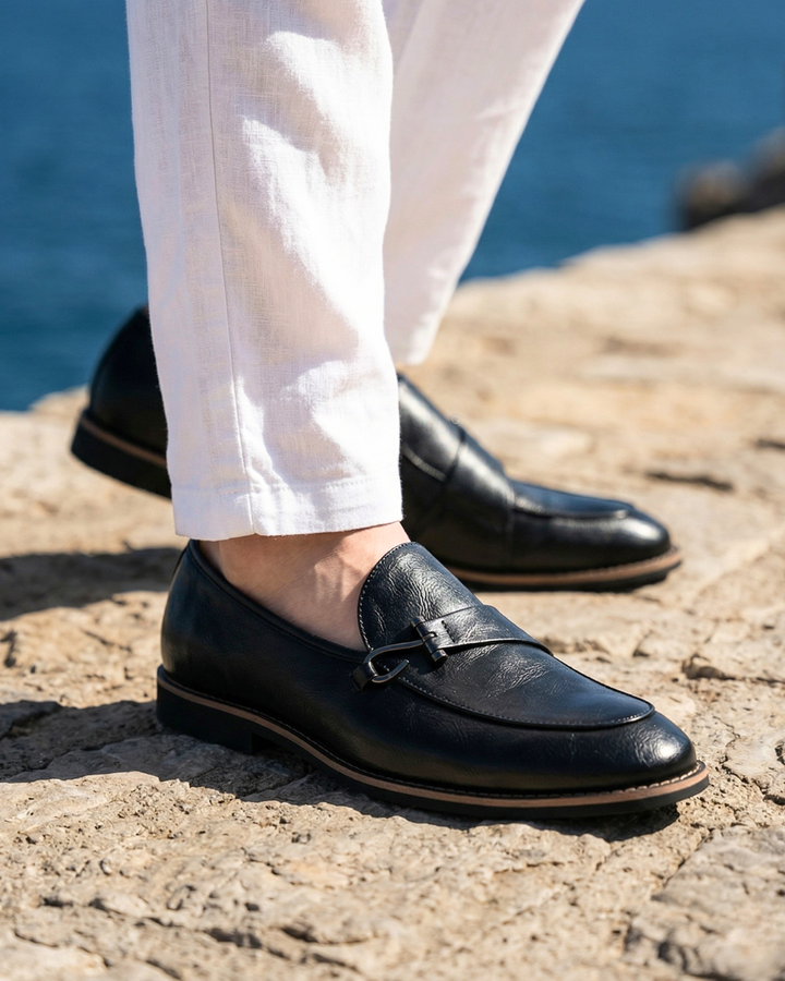Black leather nautical loafer with metal bit detail, worn with white pants
