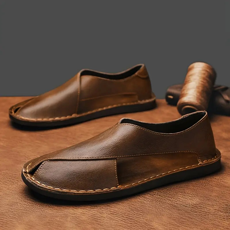 Brown leather open-toe slide sandals, shown as a pair with stitched strap detail.