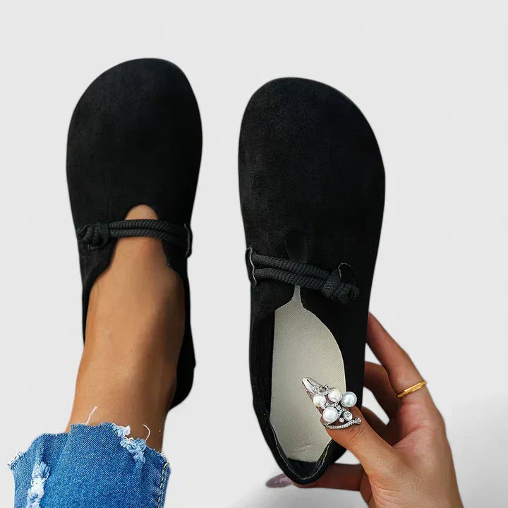 Black slip-on flats with rope detail across the instep and rounded toe