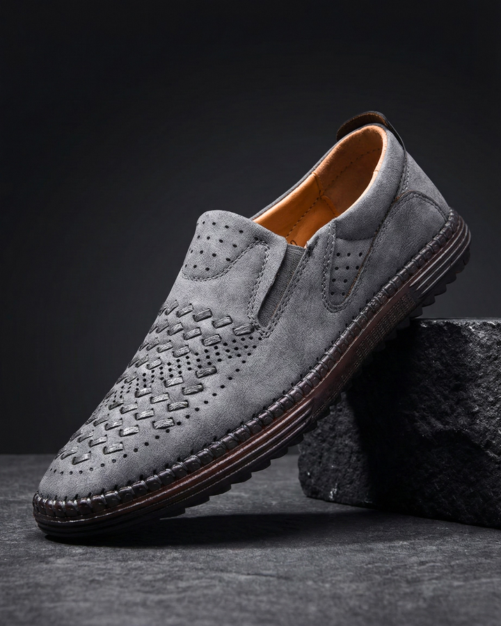 Gray leather loafer with perforated moc-toe pattern and dark stitched sole edge