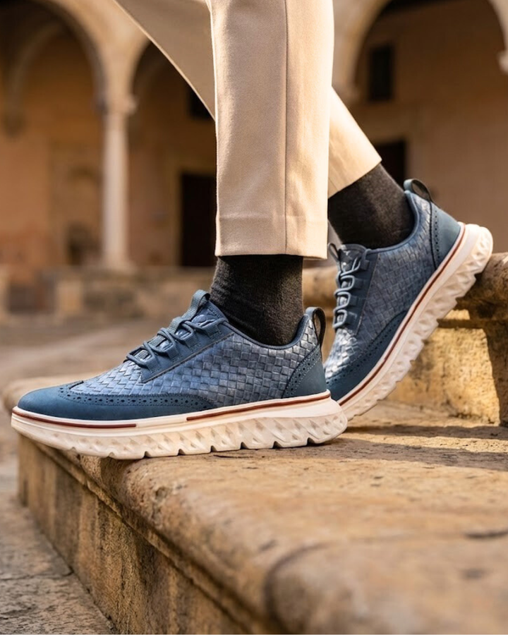 Blue lace-up dress sneaker on foot with woven-look upper and white traction outsole
