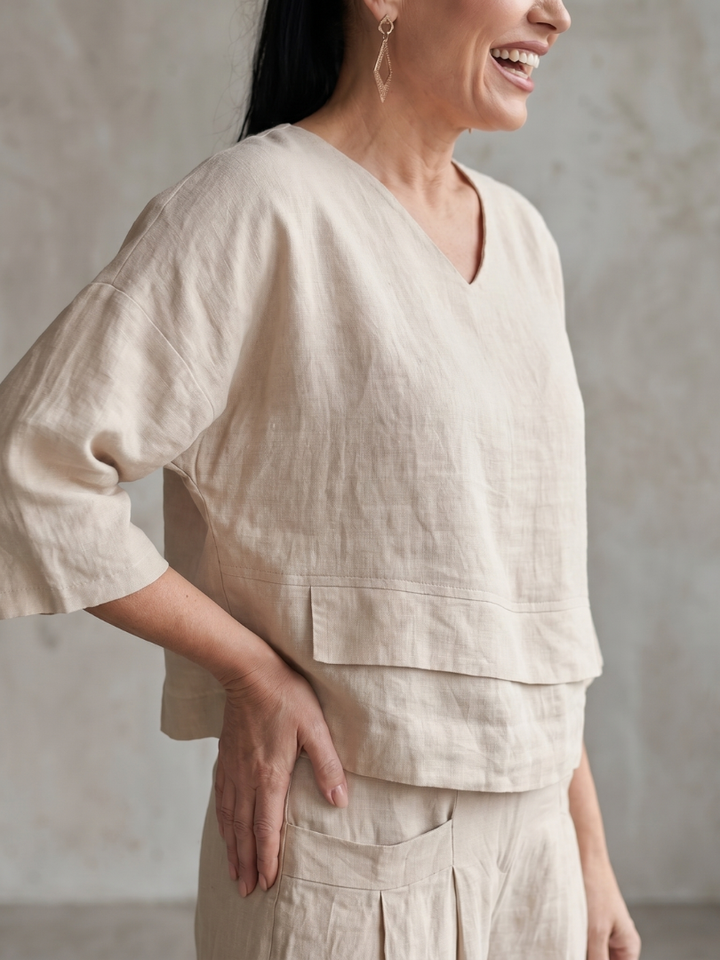 Beige wide-leg pants set with V-neck tunic top and tiered hem detail.