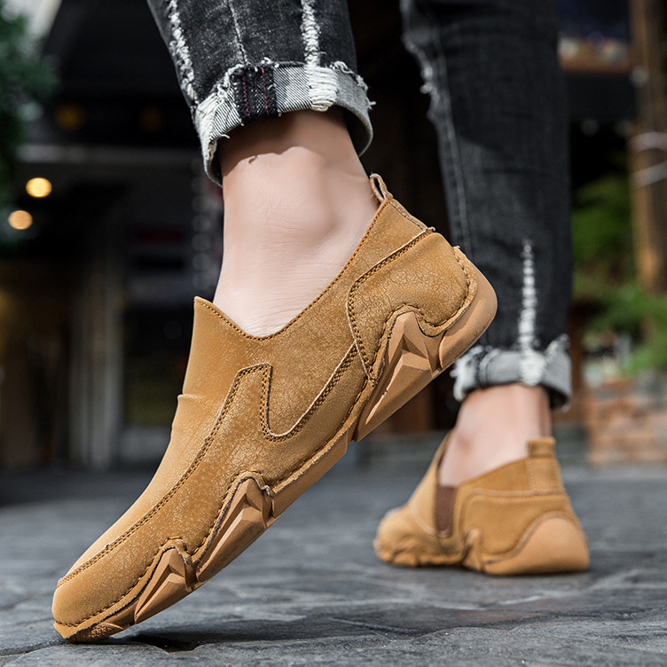 Brown slip-on loafers on model foot, moc-toe stitching and chunky rubber sole.