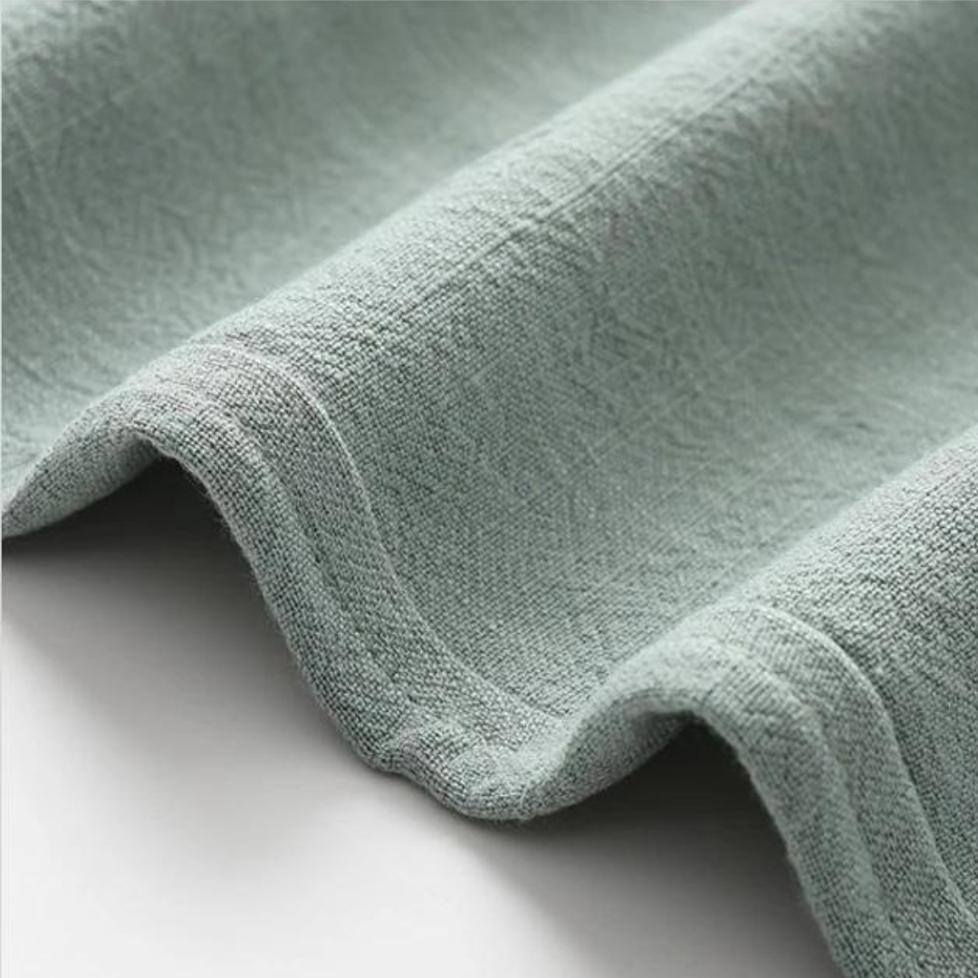 Light green linen fabric close-up with soft textured weave and drape