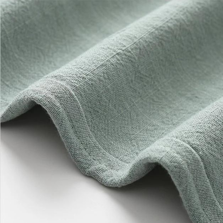 Light green linen fabric close-up with soft textured weave and drape