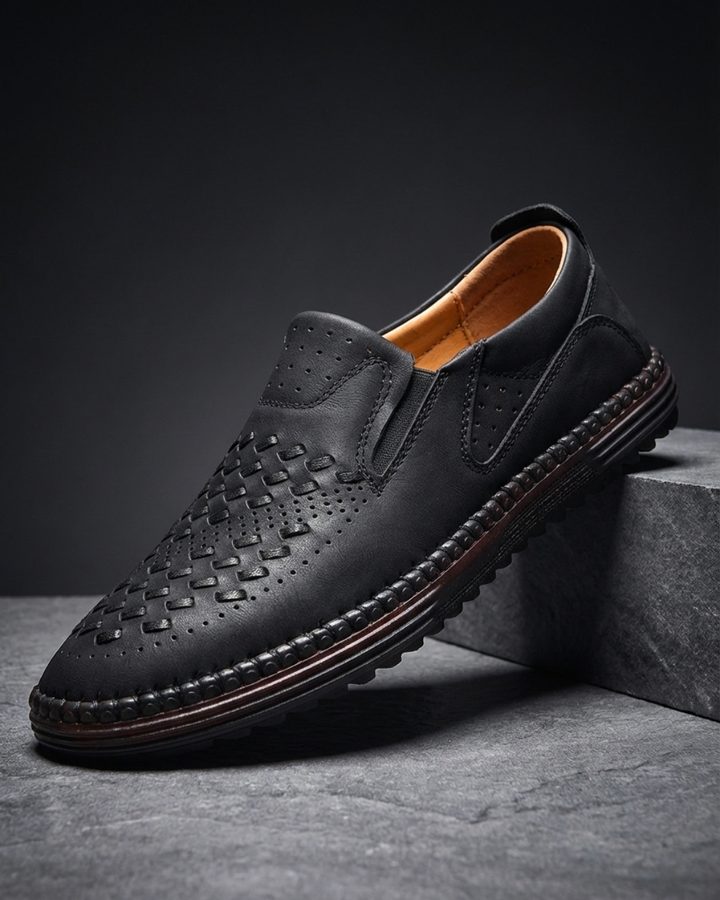 Black leather loafer with perforated moc-toe pattern and striped stitched sole