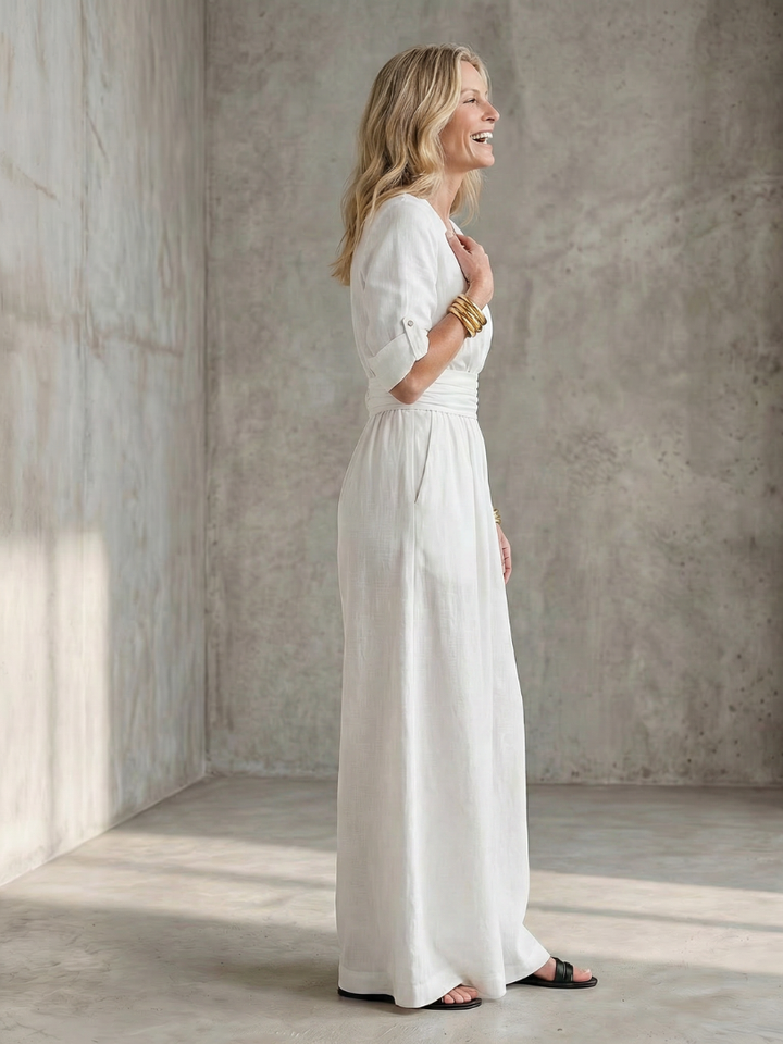 White wide-leg wrap jumpsuit, side view with tie waist and flowing wide pant legs