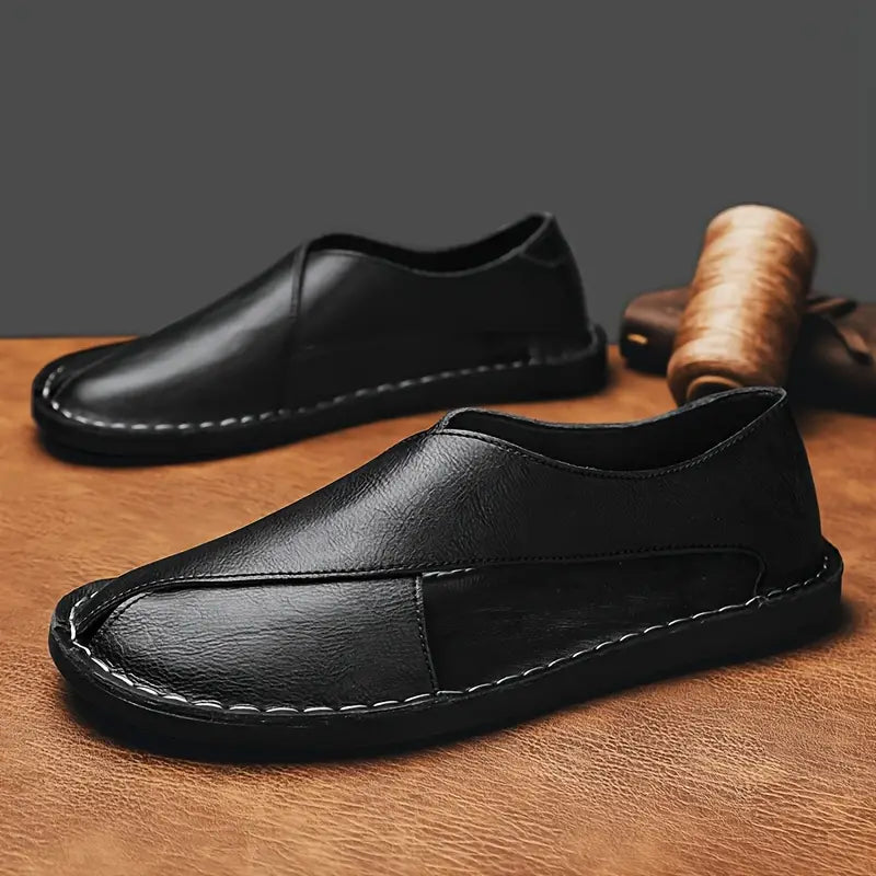 Black leather closed-toe sandals with stitched trim and low slip-on profile