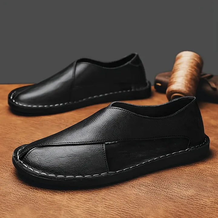 Black leather closed-toe sandals with stitched trim and low slip-on profile