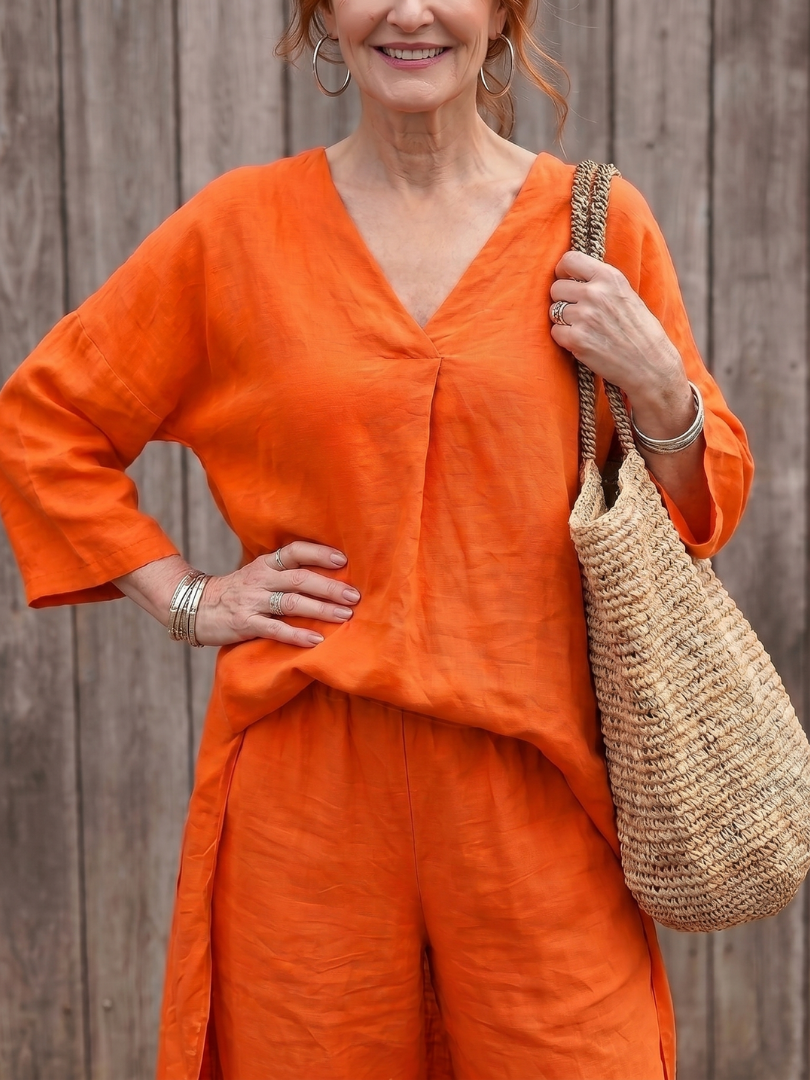 Orange linen two-piece set with V-neck tunic top and wide-leg pants, relaxed fit.