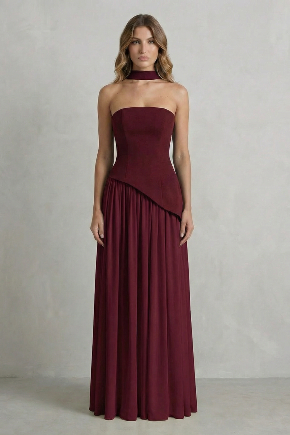 Burgundy strapless draped maxi dress with asymmetric overlay and gathered pleat hem