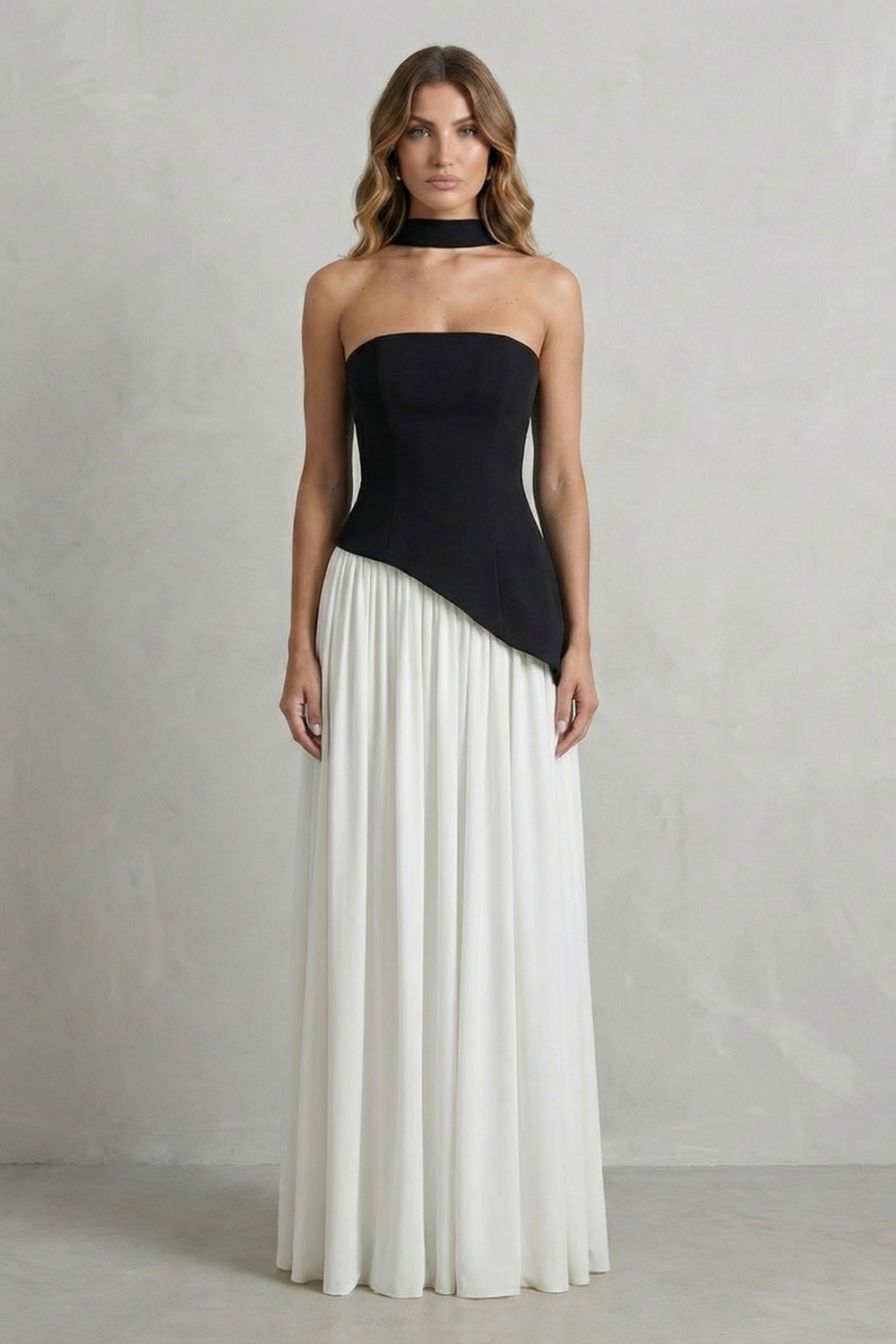 Black strapless draped maxi dress with diagonal overlay and pleated white skirt