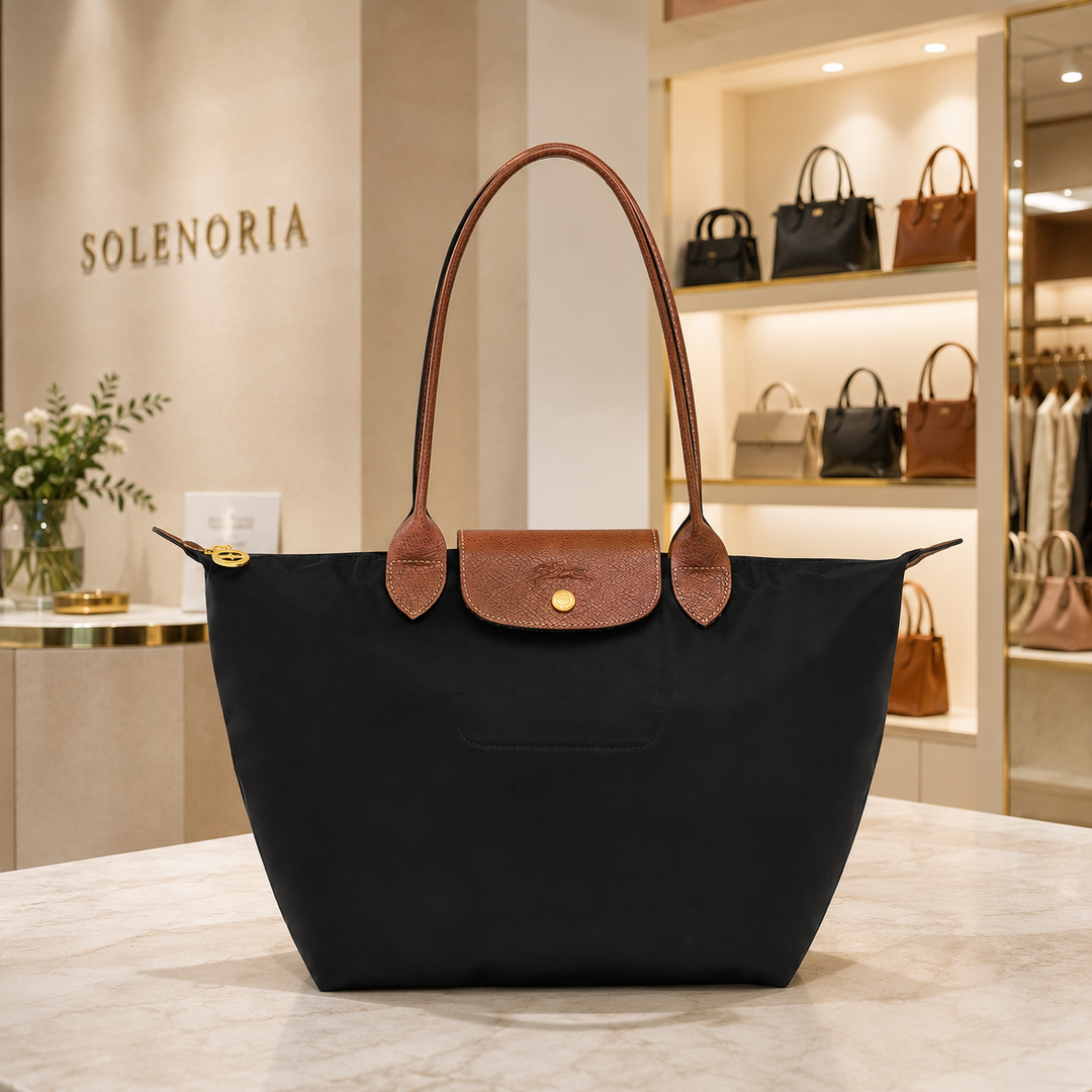 Medium black tote bag with brown leather handles and front patch pocket with gold snap