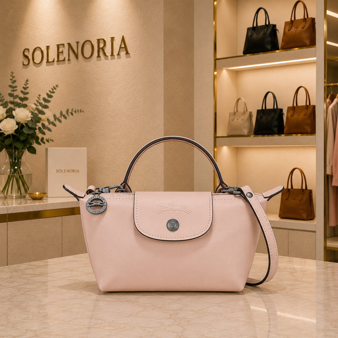 Pink mini leather tote bag with front flap, round logo, top handles and shoulder strap