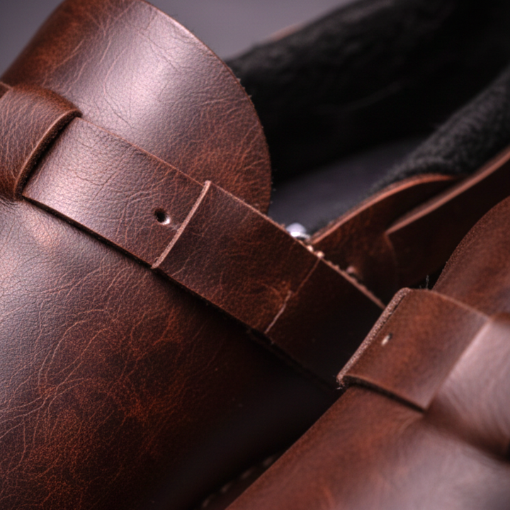 Brown leather loafer close-up: buckle strap, stitched seams, and textured upper