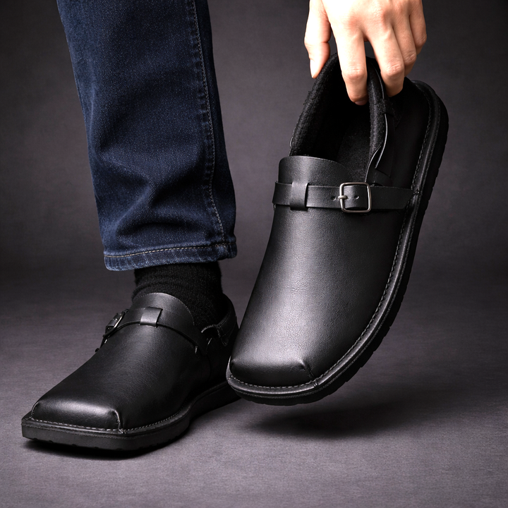 Black leather loafers with buckle strap, shown being worn with jeans and socks