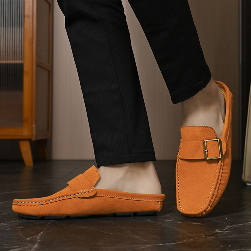 Brown suede slip-on loafers with buckle strap and stitched moccasin trim, standing view