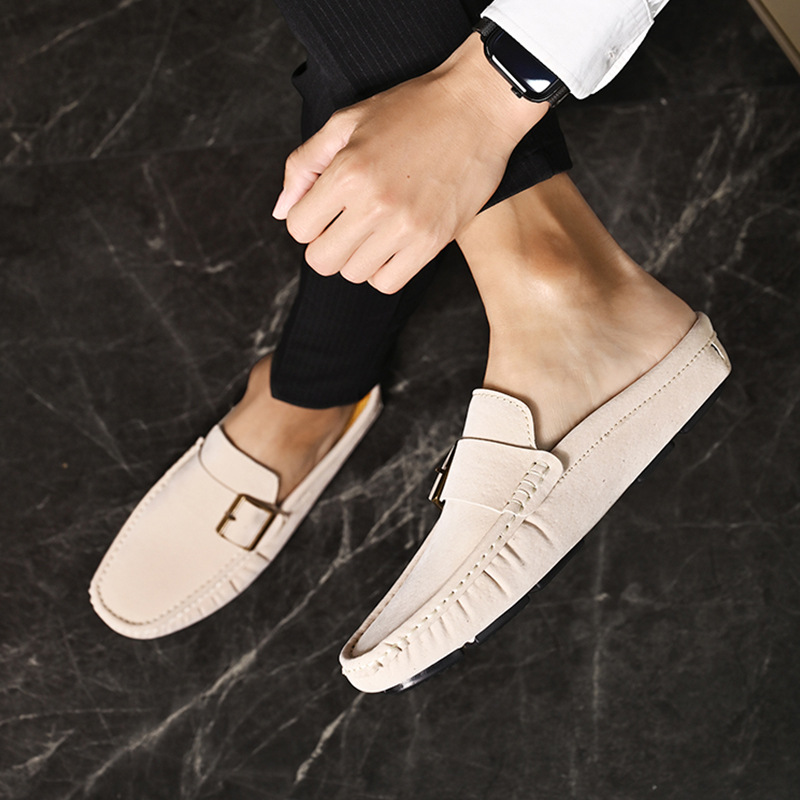 Cream suede loafers with metal buckle strap, close-up side angle on feet