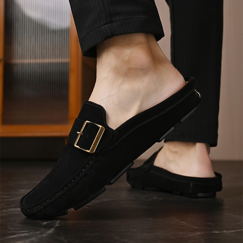 Black suede loafers with gold-tone buckle strap worn with dark trousers