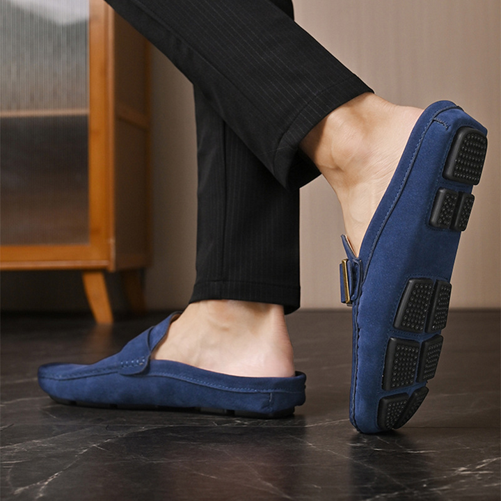 Navy suede loafers showing treaded sole with gold buckle strap