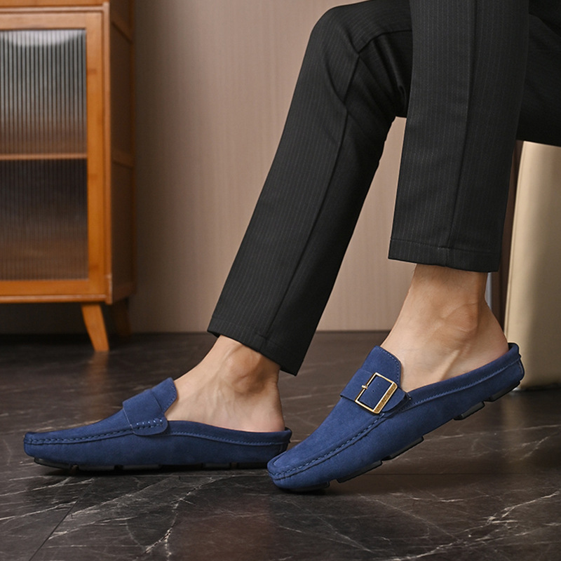 Navy suede loafers worn with dark pants, gold buckle strap