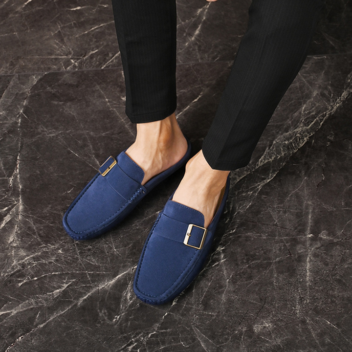 Navy suede loafers with gold buckle strap, worn with dark pants